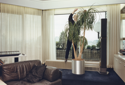 360058 Afbeelding van een man die een kamerplant verzorgt, vermoedelijk in het appartementencomplex in het ...